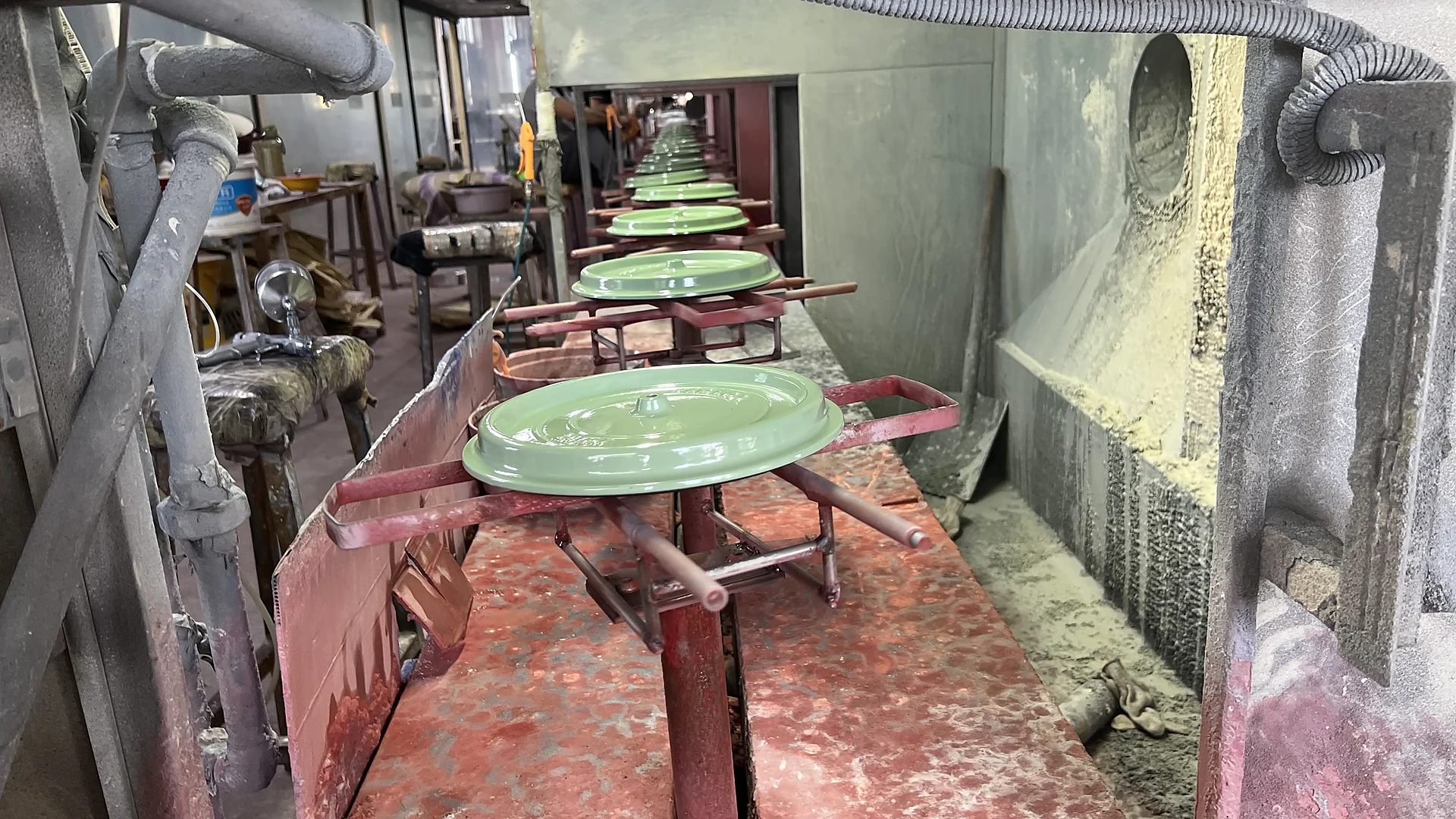 Green enameled cast iron lids on the glazing conveyor line