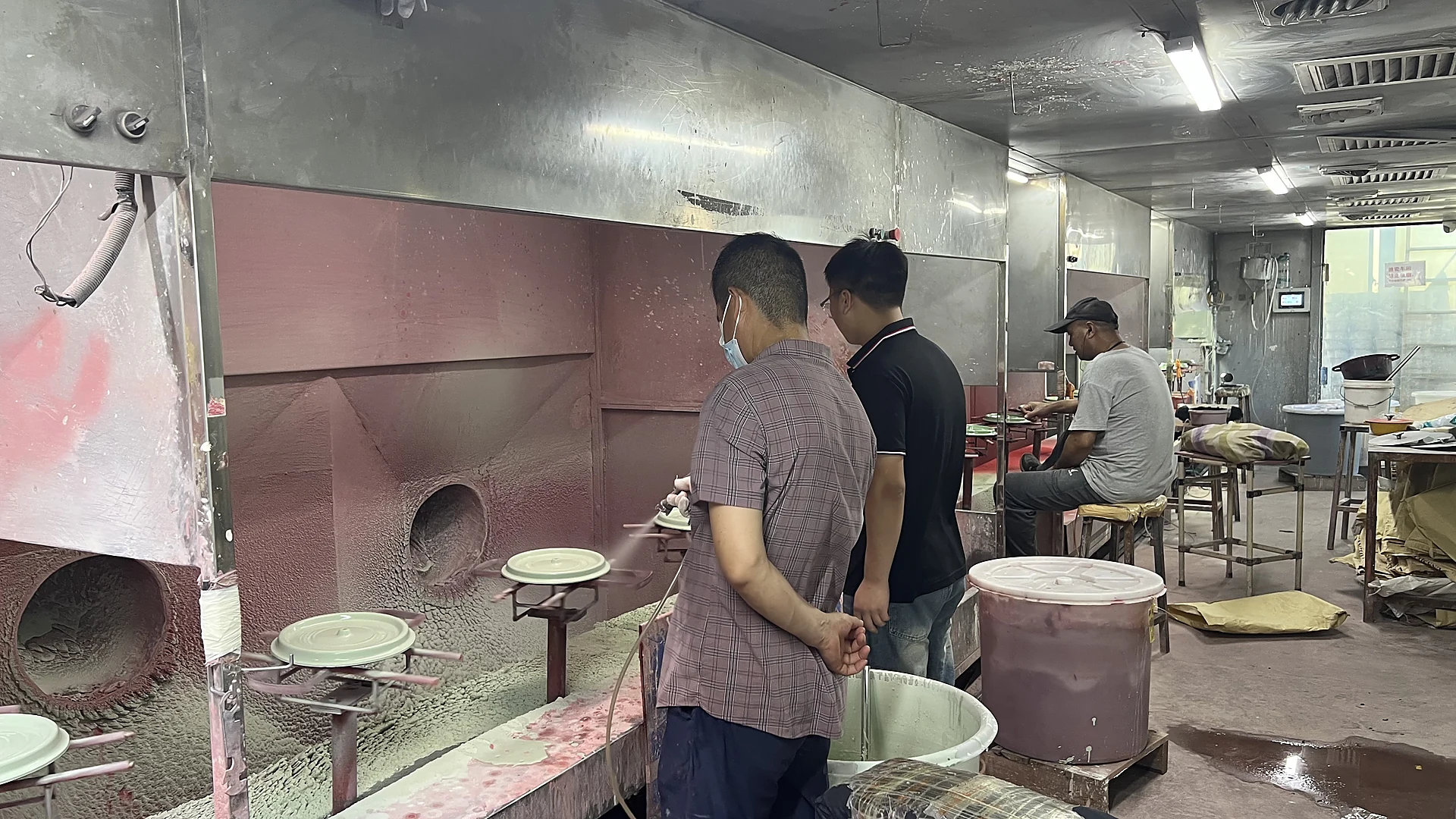 Workers checking enameled cast iron lids at the spraying booth