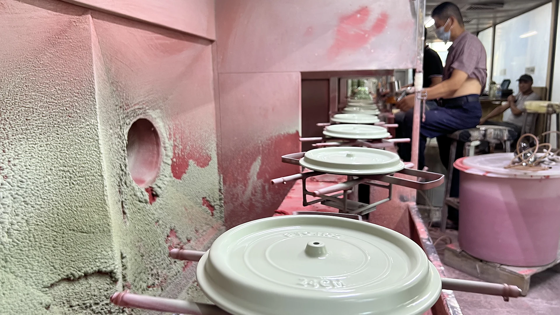 White enameled cast iron lids moving through the enamel spraying line