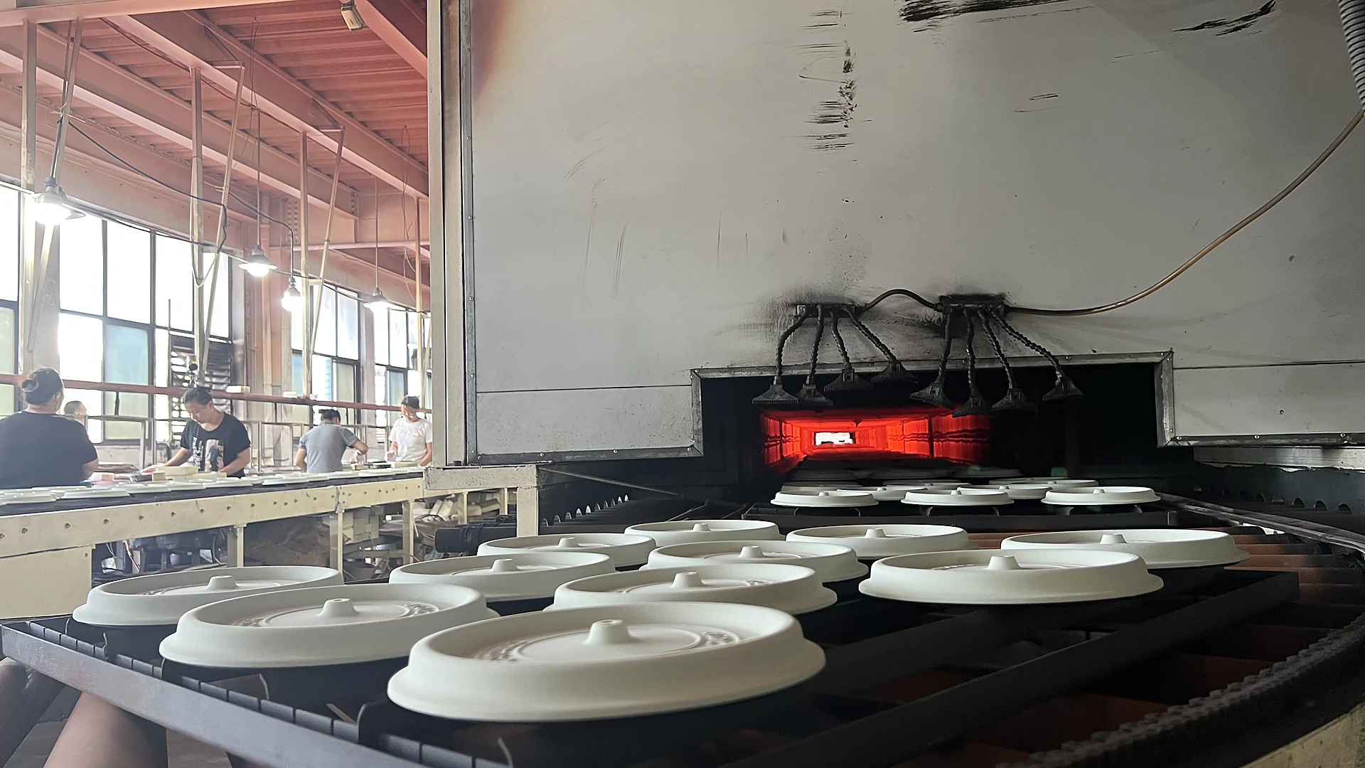 White enameled cast iron lids on the kiln conveyor before firing