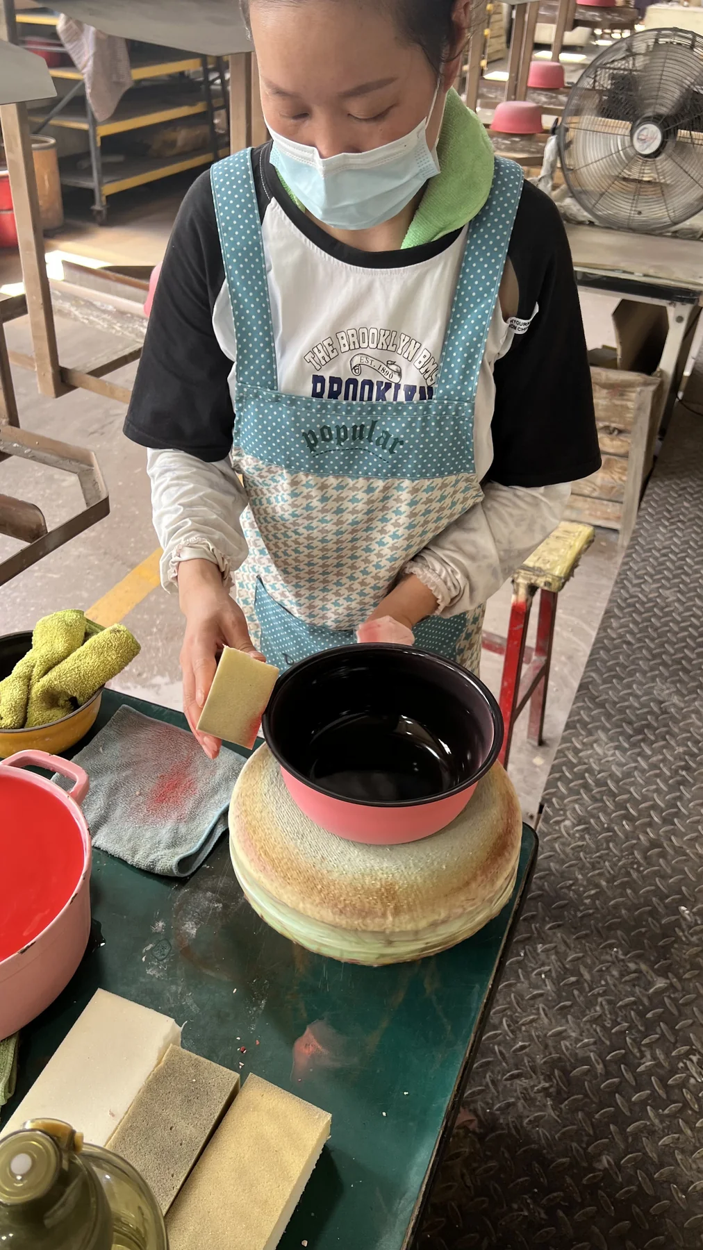 Worker checking lid fit and rim condition on an enameled cast iron casserole