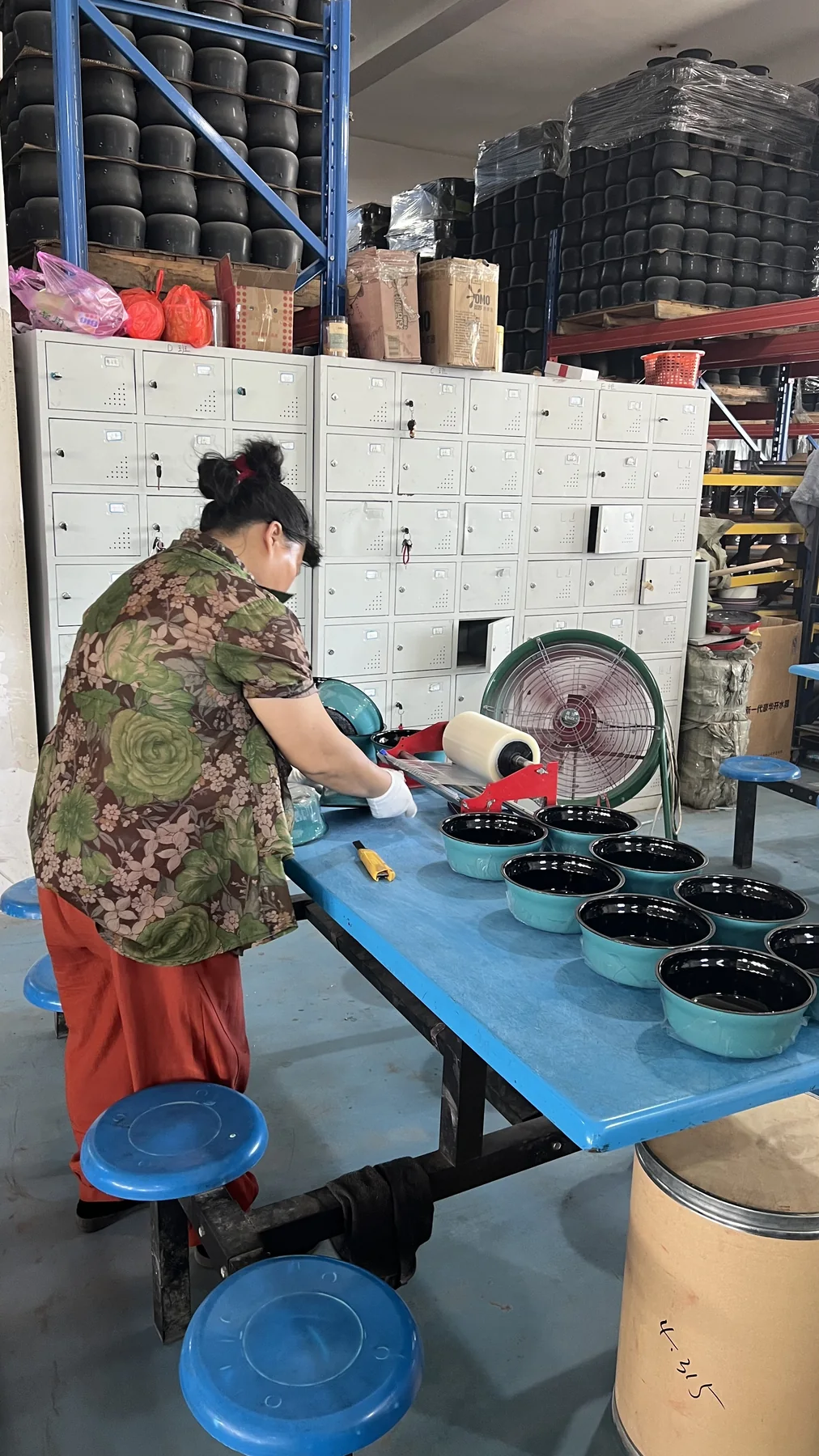 Worker checking enamel cookware surface during quality inspection