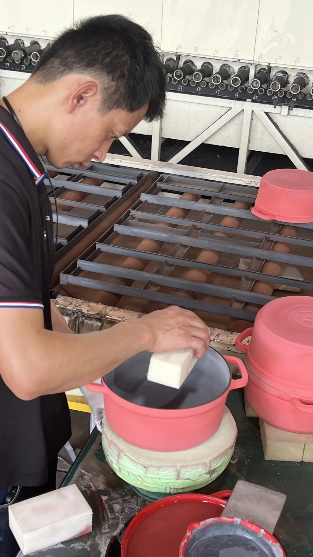 Worker checking enameled cast iron lid surface before packing